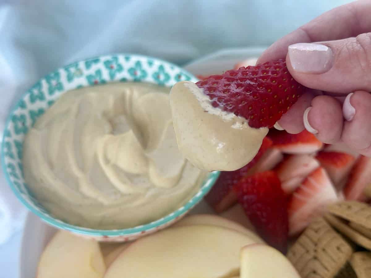 cut strawberry dipped in peanut butter dip bowl of dip cut fruit green kitchen towel
