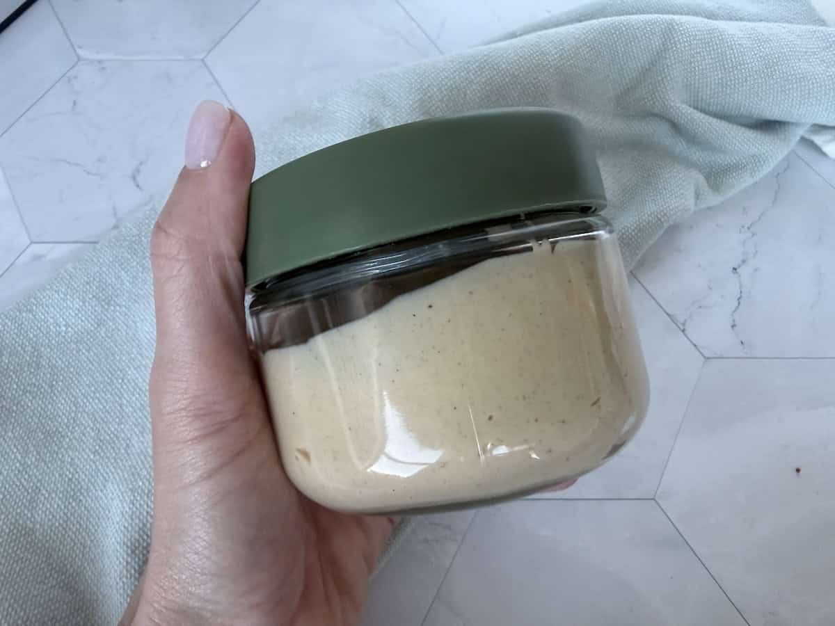 hand holding glass jar of dip with green lid