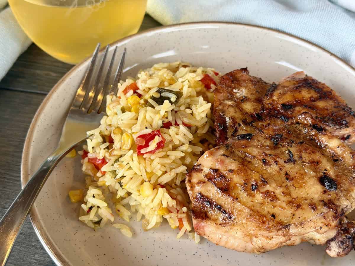 saffron and roasted pepper rice with grilled chicken tan plate glass of wine green kitchen towel