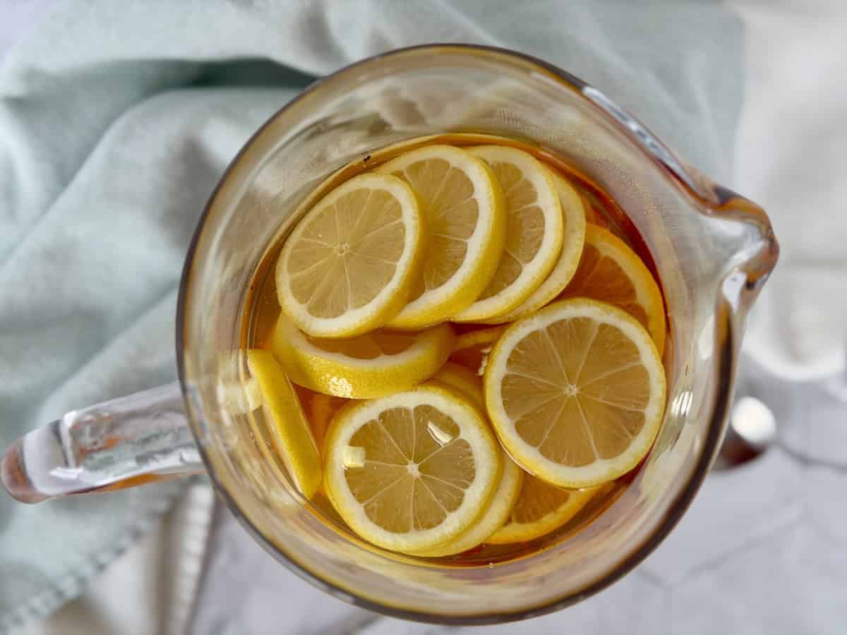 top of pitcher full of sangria and sliced lemons green kitchen towel
