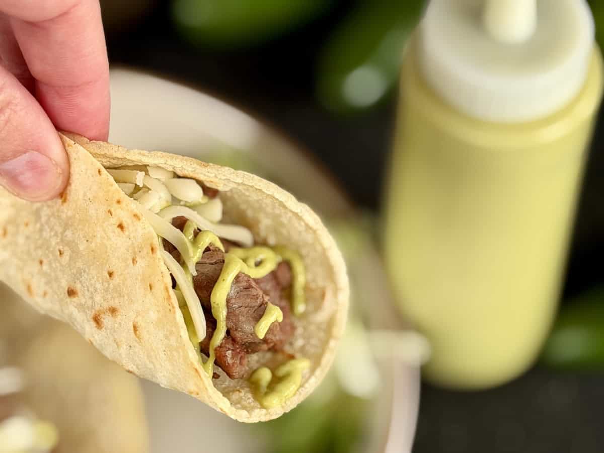 carne asada with bottle of green taco sauce
