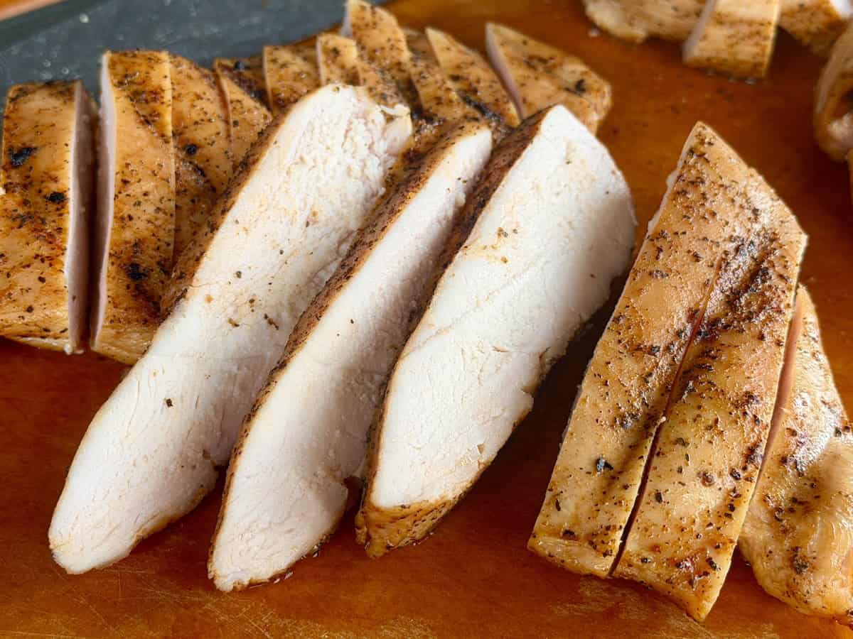 sliced traeger chicken breast on wood cutting board
