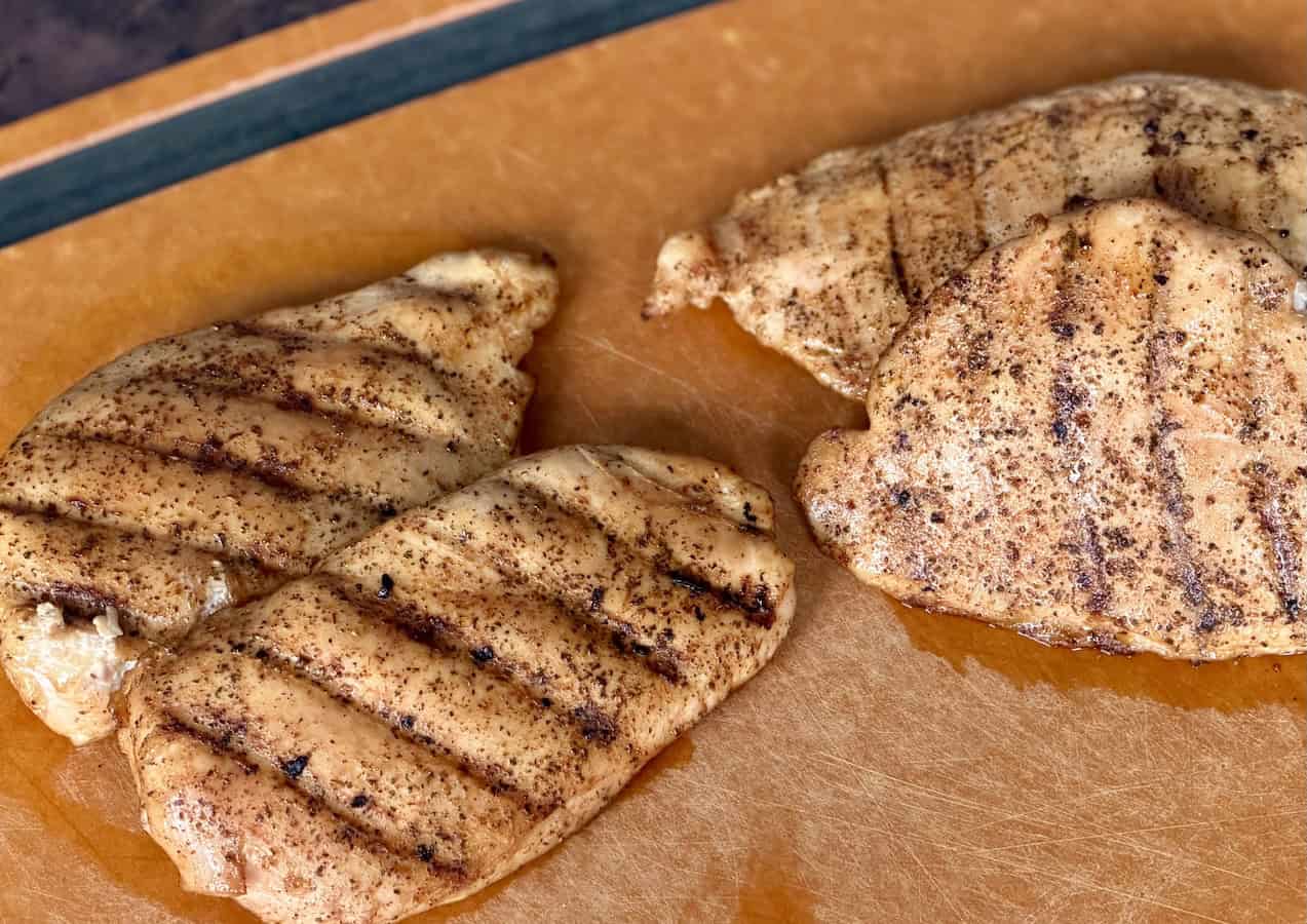 4 grilled chicken breasts on wood cutting board