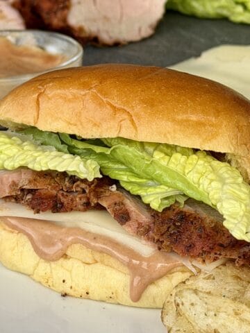pork tenderloin sandwich on white plate potato chips