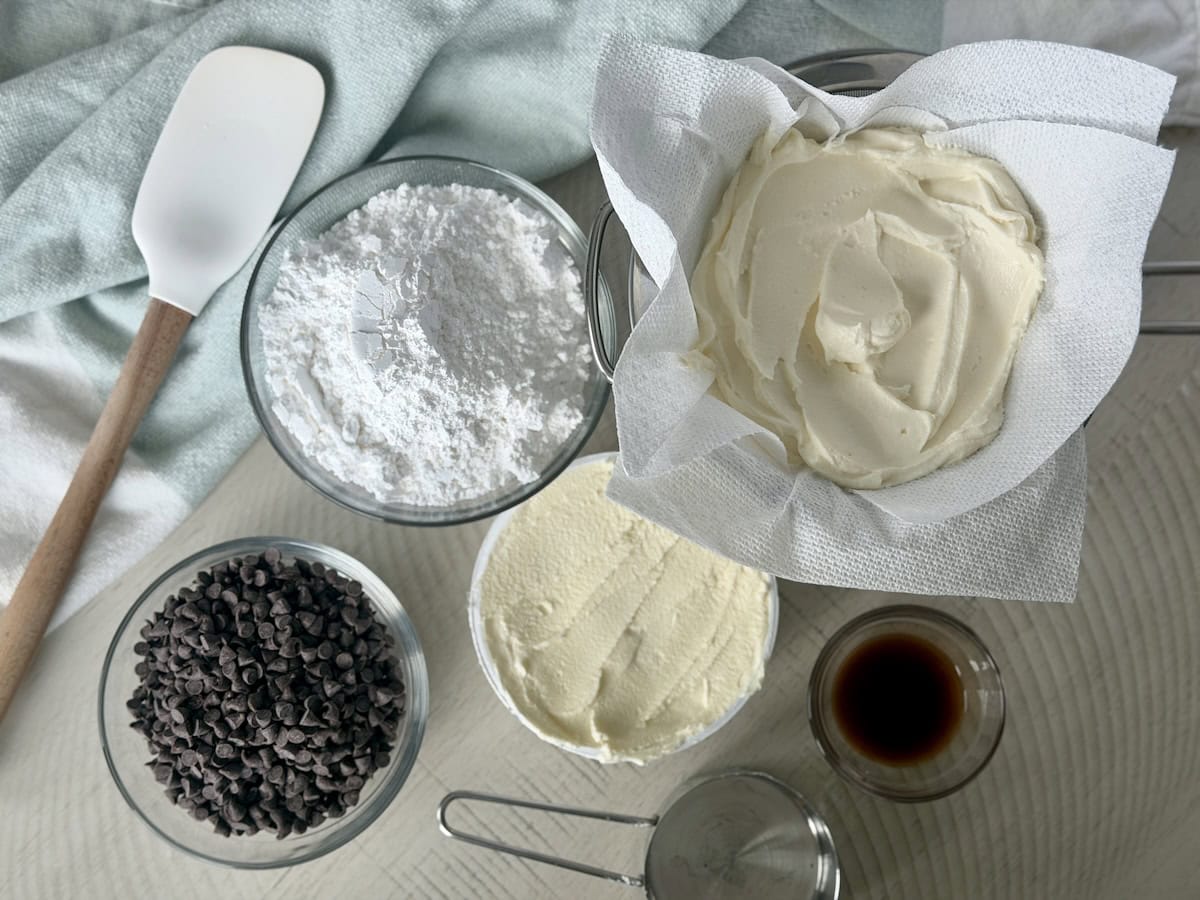 glass bowls of mini chocolate chips powdered sugar ricotta cheese marscapone and vanilla extract rubber spatula green towel