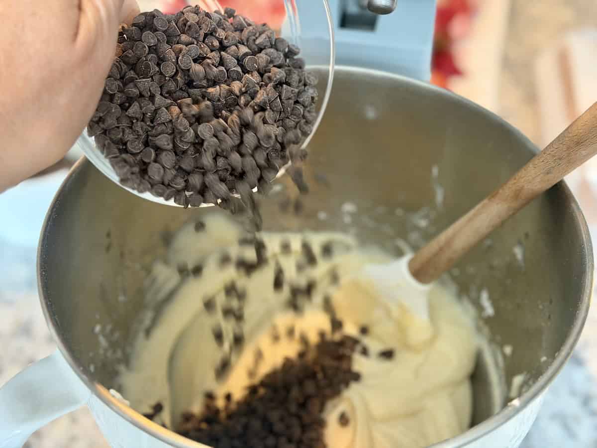 mini chocolate chips pouring into mixing bowl with cannoli dip