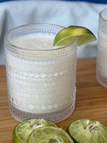 Brazilian lemonade in glass lime wedge squeezed lime halves