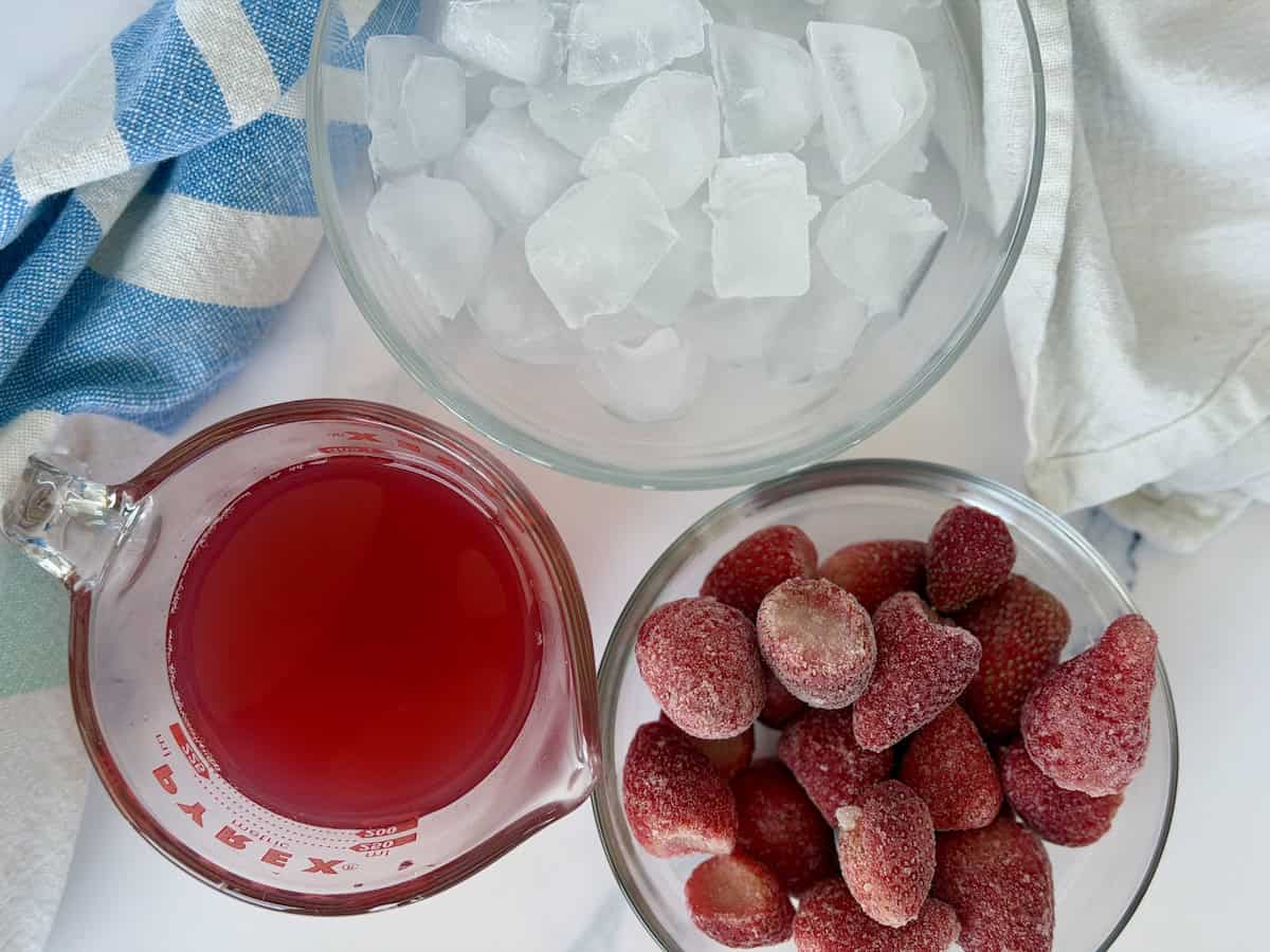 glass bowls of ice fruit juice and frozen strawberries with green and blue kitchen towel