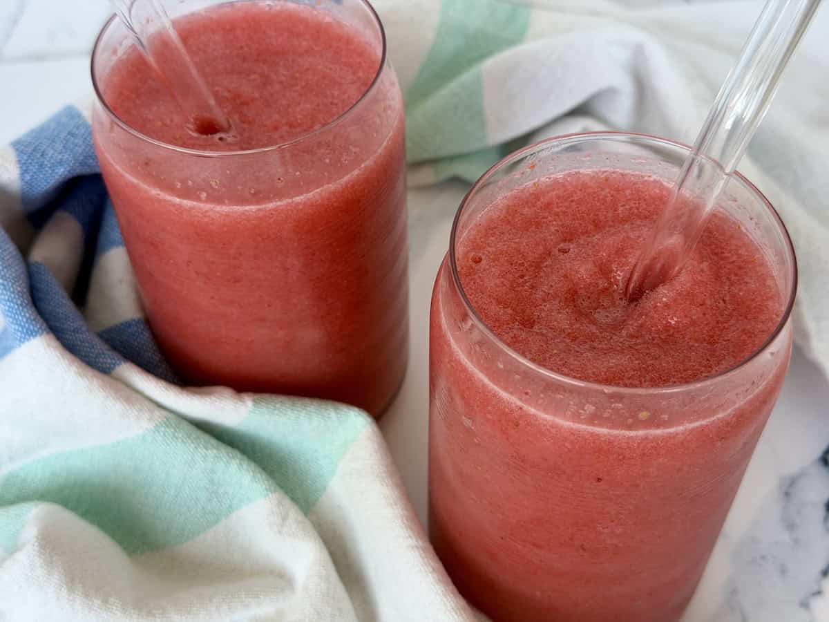 2 strawberry fruit slushies green kitchen towel white marble countertop