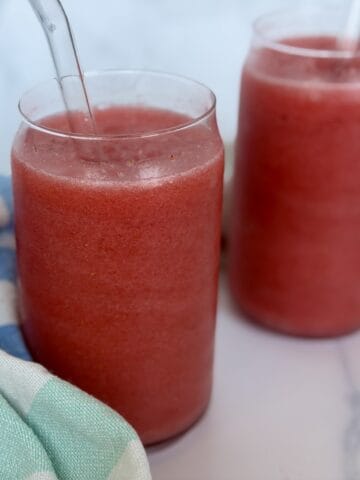 2 strawberry fruit slushies green kitchen towel white marble countertop
