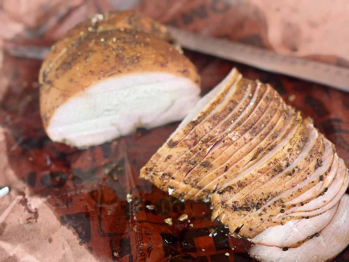 sliced smoked turkey breast on pink butcher paper slicing knife