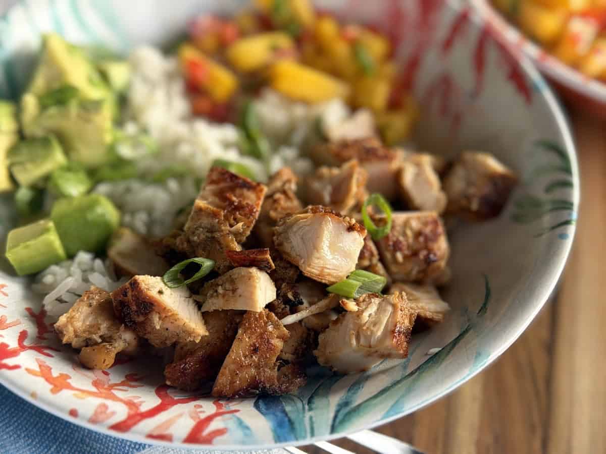 jerk chicken rice bowl in tropical bowl on wood cutting board