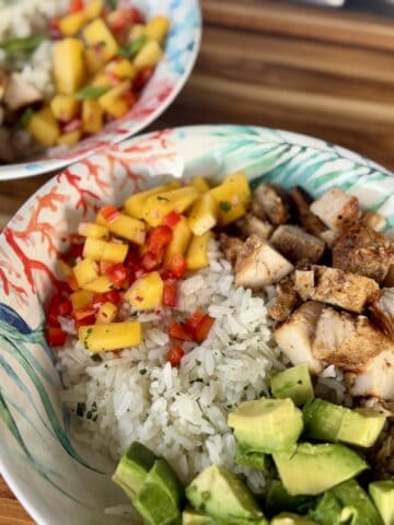 jerk chicken rice bowl in tropical bowls on wood cutting board