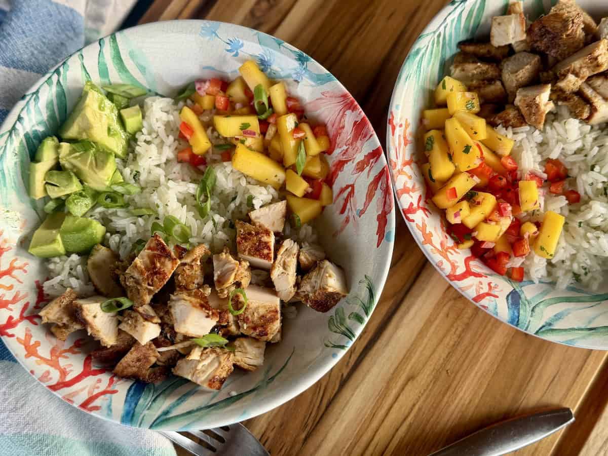 jerk chicken rice bowl in tropical bowls on wood cutting board